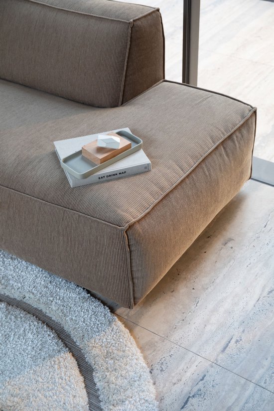 Gros plan d'un canapé en velours côtelé marron avec un plateau décoratif contenant des livres.