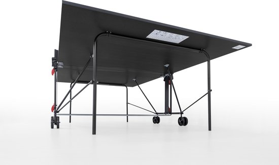 De onderkant van een zwarte tafeltennistafel met een metalen frame en wieltjes. De tafel is schuin omhoog gekanteld.
