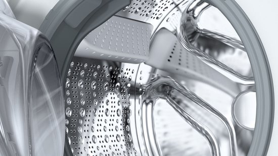 Close-up van de binnenkant van een metalen wasmachinetrommel met waterdruppels.