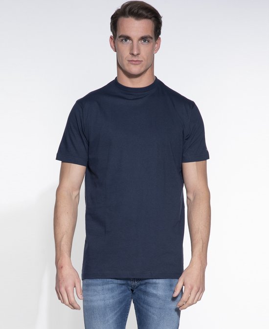 Model in een effen donkerblauwe T-shirt met korte mouwen en ronde hals, gecombineerd met een spijkerbroek.