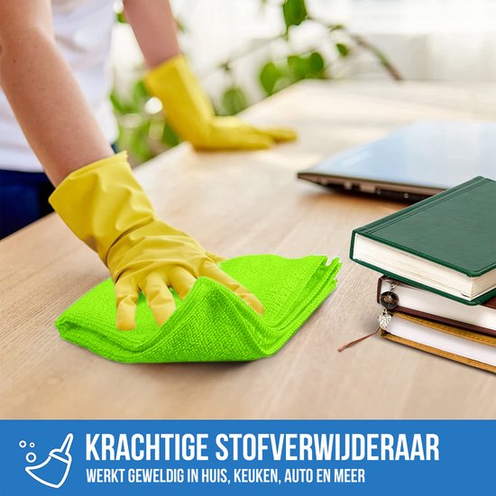 Une main gantée de jaune déplace un chiffon microfibre vert vif sur une table en bois.