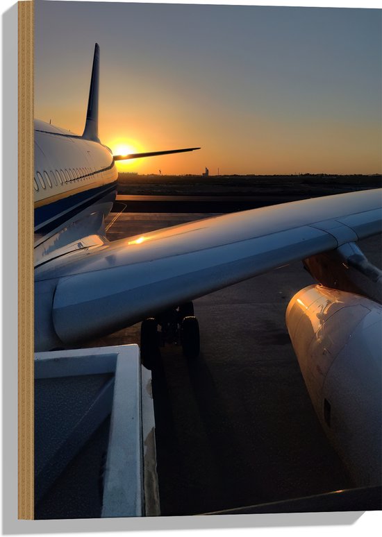 Coucher de soleil sur le côté d'un avion blanc, aile et moteur visibles.