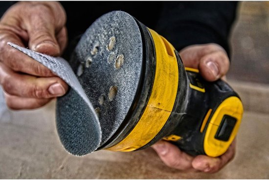 Handen bevestigen een schuurschijf aan de DeWalt excentrische schuurmachine.