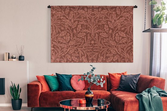 Wandkleed met bruin bloem- en bladerpatroon in een moderne woonkamer boven een roestbruine bank.