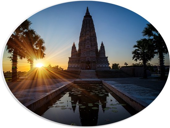 PVC Schuimplaat Ovaal - Ondergaande Zon Verdwijnend achter Wat Panyanantarm Tempel in Thailand - 40x30 cm Foto op Ovaal (Met Ophangsysteem)