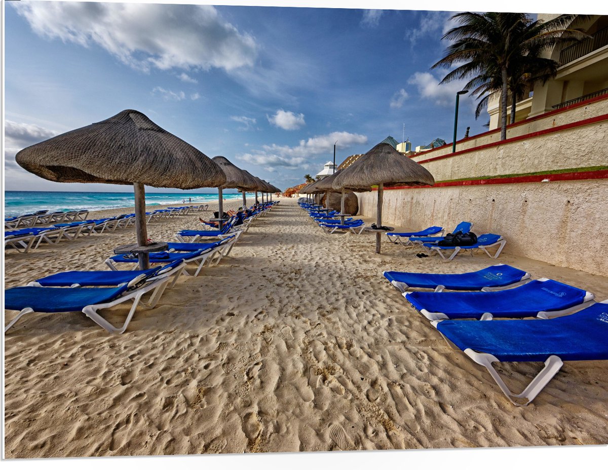 PVC Schuimplaat- Blauwe Ligbedden op Strand met Rieten Parasols - 100x75 cm Foto op PVC Sc