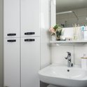 Witte badkamermeubels met zwarte handgrepen, wastafel en spiegel.