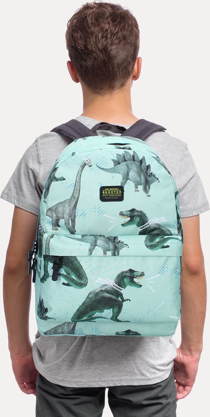 Jongen draagt een lichtblauwe rugzak met dinosaurusprint op zijn rug.