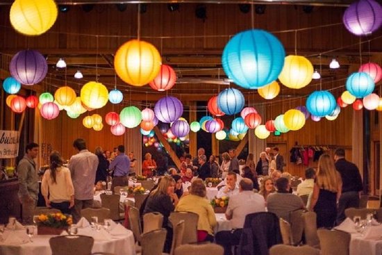 Gasten genieten van een feest onder kleurrijke lampionnen.