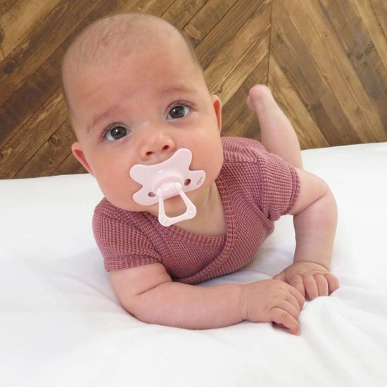 Baby met een roze Difrax fopspeen op een witte ondergrond.