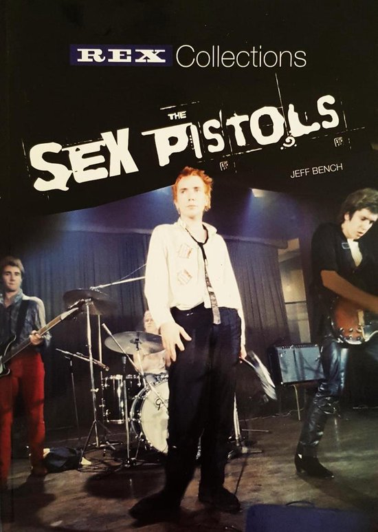 Drie muzikanten op een podium tijdens een optreden. Een zanger staat in het midden met een wit shirt, een drummer achter hem, en een gitarist links.