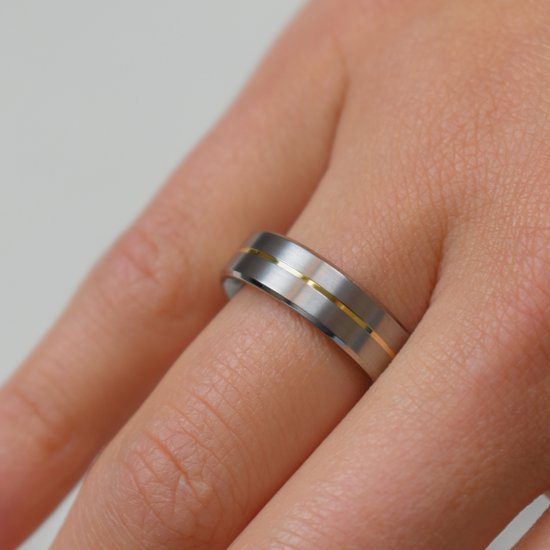 Titanium ring met gouden band, gedragen op een vinger.