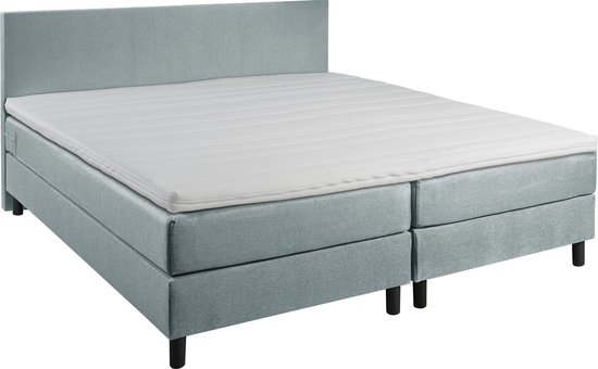 IJsblauw boxspringbed met hoofdbord, twee boxen en een matras met topper.