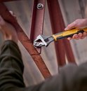 Stanley verstelbare moersleutel met geel-zwarte grip wordt gebruikt om een bout aan een roestig metalen frame vast te draaien.