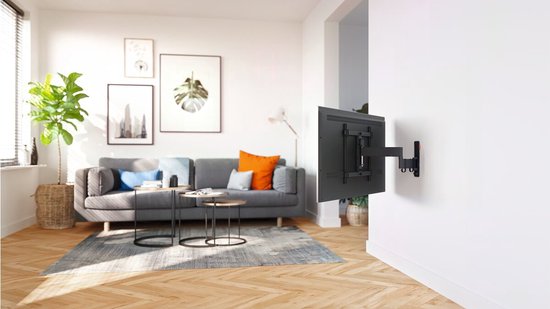 Een zithoek met een grijze bank, salontafels en een zwarte tv gemonteerd aan de muur met een tv-beugel.