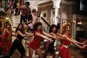 Groep vrouwen in kleurrijke kleding danst op een trap en in een woonkamer.