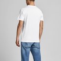 Man in een wit T-shirt en blauwe spijkerbroek, rug zichtbaar, staand.