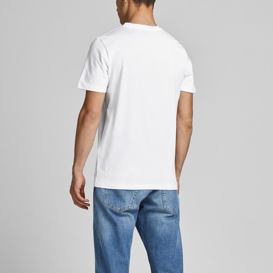 Man in een wit T-shirt en blauwe spijkerbroek, rug zichtbaar, staand.