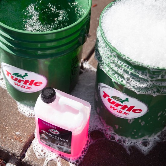 Fles Turtle Wax Snow Foam Shampoo naast twee groene emmers, één met schuim.