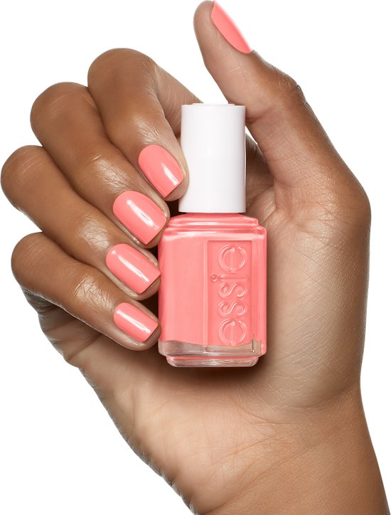 Donkere hand met Essie nagellak in een warme koraalkleur, korte nagels, witte dop.