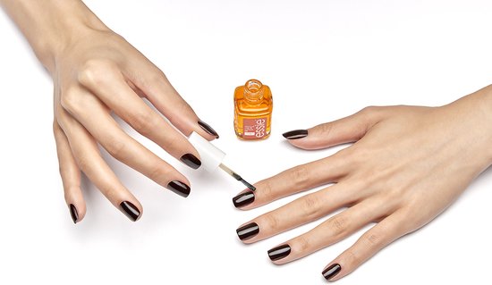 Een persoon brengt Essie apricot nail & cuticle oil aan op haar nagels. De nagels zijn donkerrood gelakt.