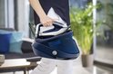 Persoon in donkerblauwe top en witte broek draagt het donkerblauwe Tefal Pro Express Vision stoomstrijkijzer.