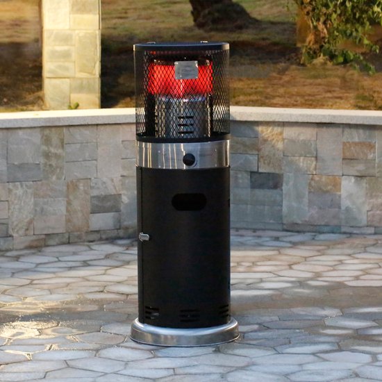 Zwarte staande terrasverwarmer met zilverkleurige details, op een betegeld terras bij een stenen muur.