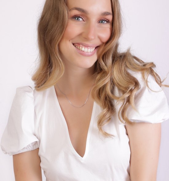 Glimlachende blonde vrouw met een zilverkleurige gourmet schakelketting van 45 cm, gedragen met een witte top.