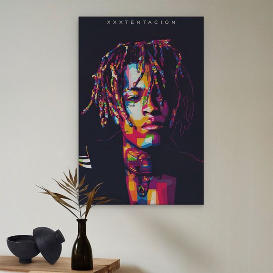 Abstract, kleurrijk portret van XXXTentacion op canvas, hangend aan een muur met plant.