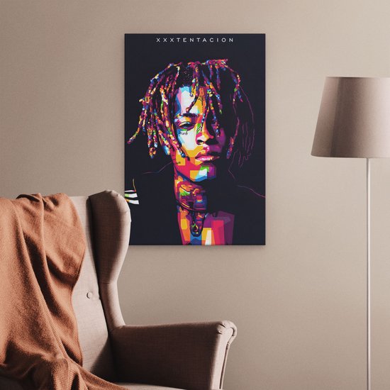 Abstract, kleurrijk portret van XXXTentacion op canvas, in een woonkamer met fauteuil.