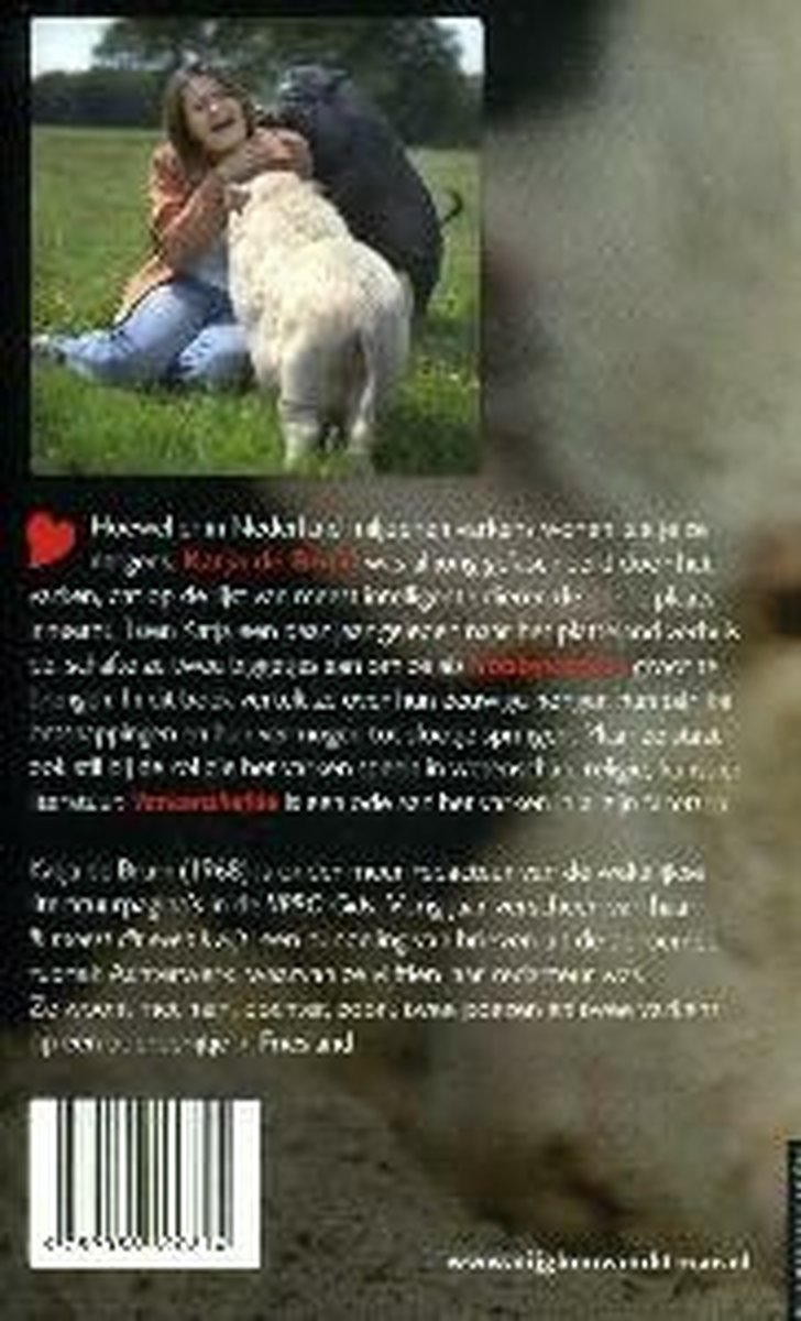 Een jonge vrouw met een bruin jasje zit op de grond, lachend met twee honden en een schaap.