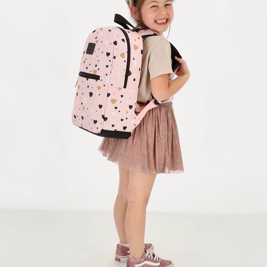 Meisje met een roze rugzak met hartjesprint, compleet met een glinsterende rok en sneakers.