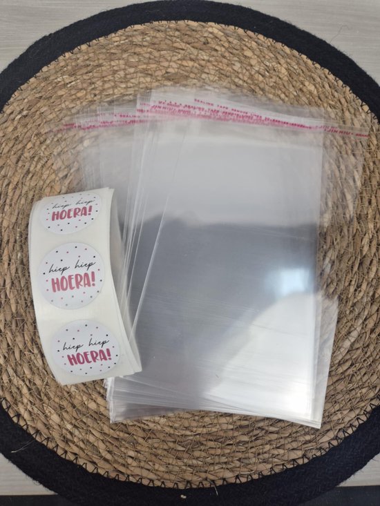 Transparante uitdeelzakjes met stickers 'hiep hiep HOERA!' op een ronde mat.