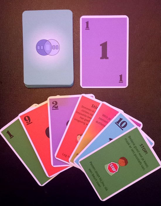 Kaarten van het spel Gomiru. Veelkleurige kaarten met cijfers en teksten, waaronder een kaart met 'STOP!' en een rood stopbord.