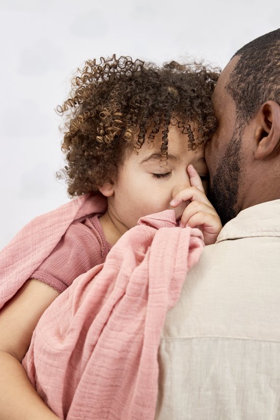 Kindje slaapt op de schouder van een man, gewikkeld in een zachtroze swaddle.