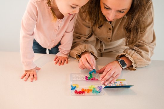 Vrouw en jong meisje spelen met gekleurde bubbelvormige spelstukken in een speldoosje.