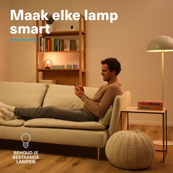Man zit op bank met smartphone. "Maak elke lamp smart. Behoud je bestaande lampen."
