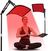 Twee rood lichttherapiepanelen en een vrouw in meditatiehouding.