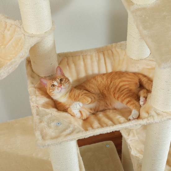 Een oranje gestreepte kat ligt ontspannen in een beige hangmat op een krabpaal.
