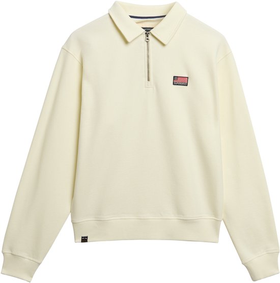 Off-white trui met halve rits, kraag en een rode, witte en blauwe patch op de borst.