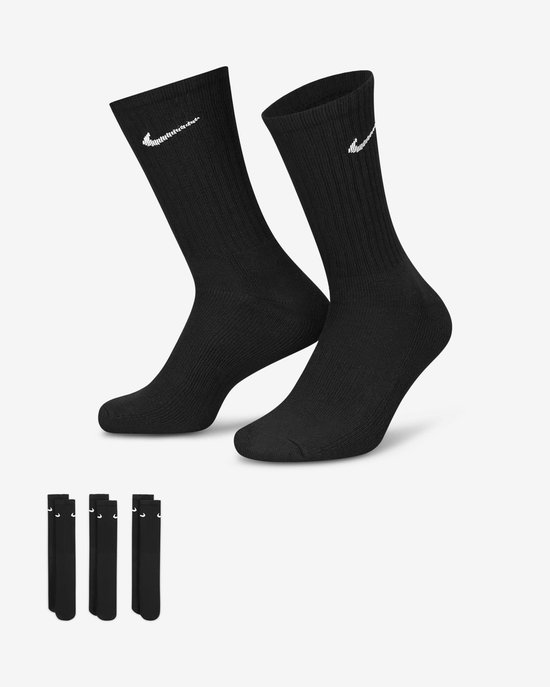 Een paar zwarte sportsokken met witte Nike 'swoosh' logo's, met extra sokken op de achtergrond.