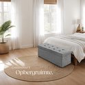 Grijze opbergkist met knopen op een ronde jute mat in een slaapkamer.