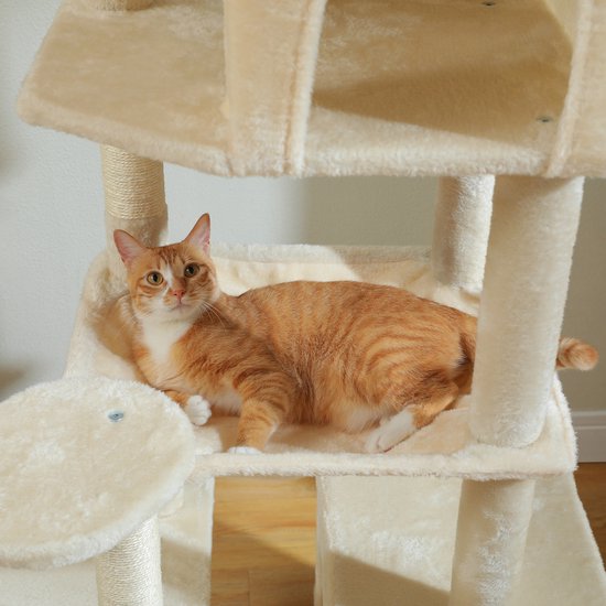 Oranje kat met witte borst en poten, liggend op een beige, zacht platform van een kattentoren.
