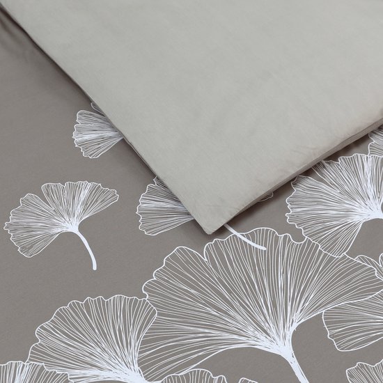 Close-up van een grijs dekbedovertrek met witte ginkgo bladeren.