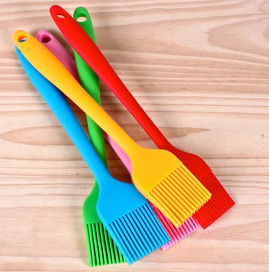 Vier siliconen bakkwasten in rood, geel, roze en groen op een houten achtergrond.