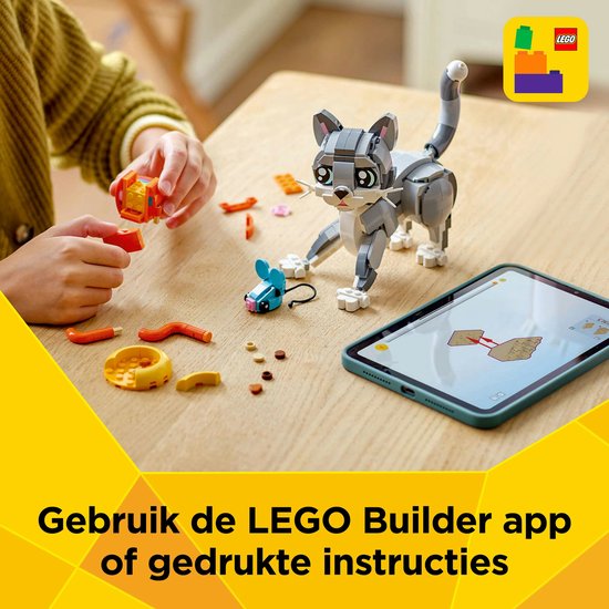 Fille construisant un chat LEGO sur une table avec des instructions sur tablette.