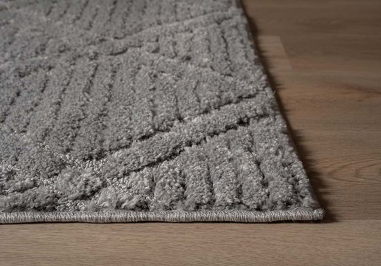 Gros plan détaillé de la texture et du motif losange géométrique d'un tapis gris clair.