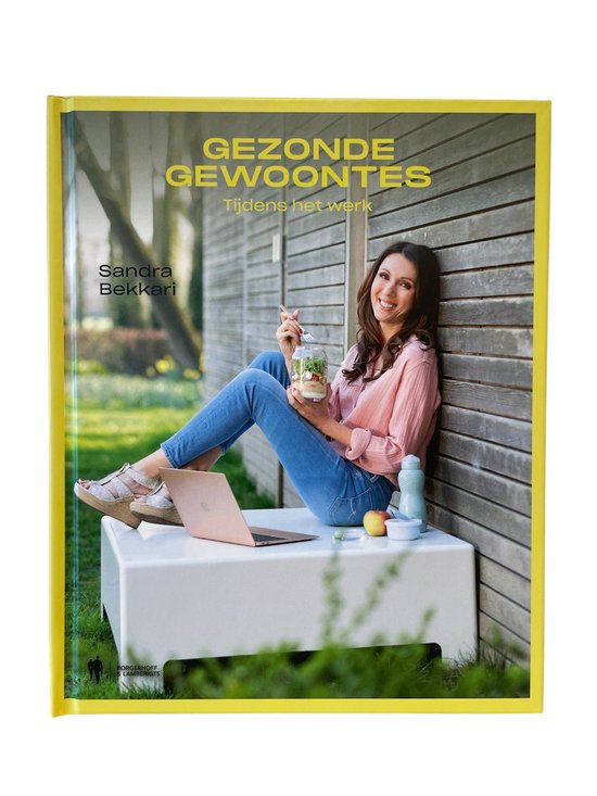 Vrouw in roze blouse en jeans, met een pot salade en laptop, voor een houten schuur.