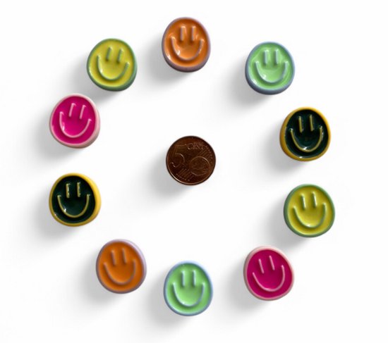 Twaalf ronde magneten met lachgezichtjes in verschillende kleuren, gerangschikt in een cirkel rond een muntstuk.