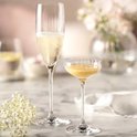 Twee champagneglazen met verticale ribbels, één gevuld met champagne, de ander met een gele vloeistof.